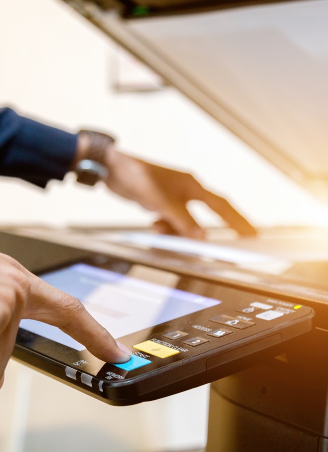 Someone placing a piece of paper and pressing a button on a copy machine