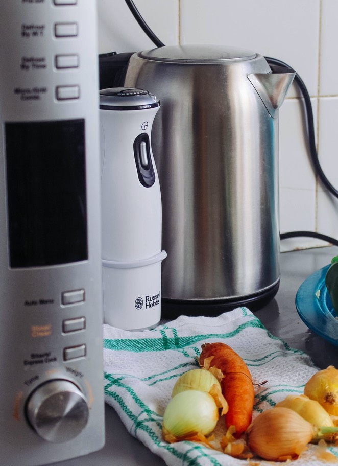 Three kitchen appliances sitting next to vegetables on a kitchen towel