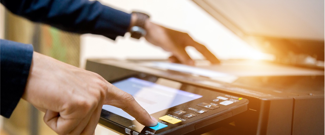 Someone placing a piece of paper and pressing a button on a copy machine