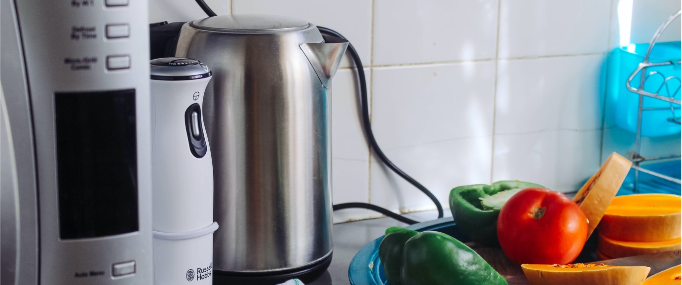 Three kitchen appliances sitting next to vegetables on a kitchen towel