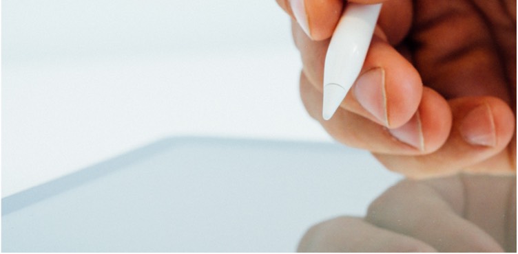 Close up of hand using a smart pen on a tablet.