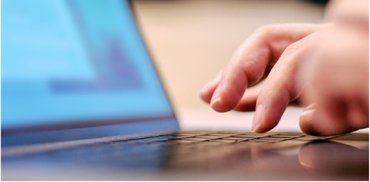 Close up image of a hand typing on a laptop