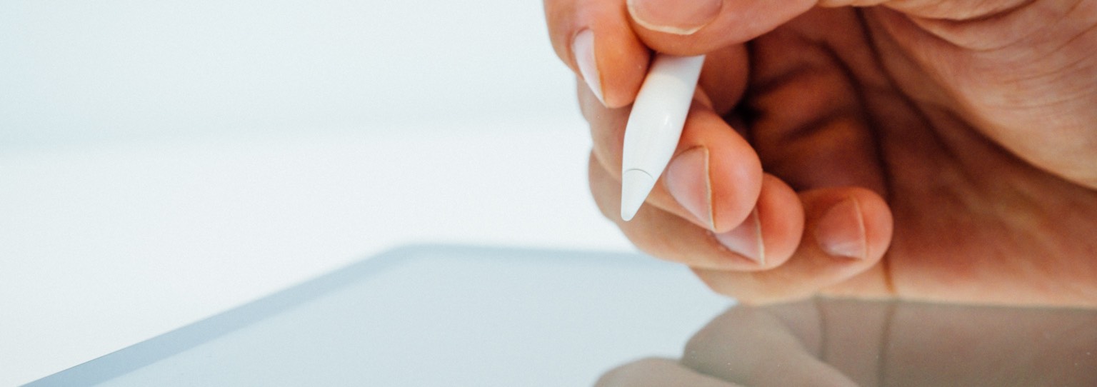 Close up of hand using a smart pen on a tablet.