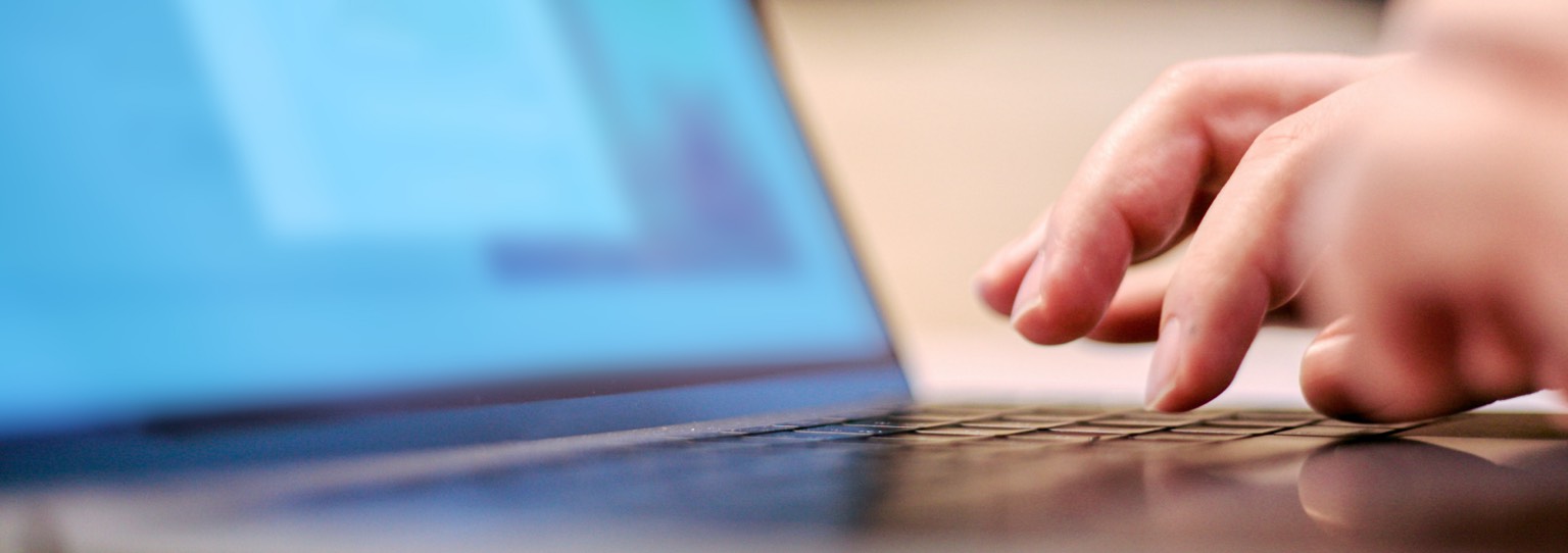 Close up image of a hand typing on a laptop