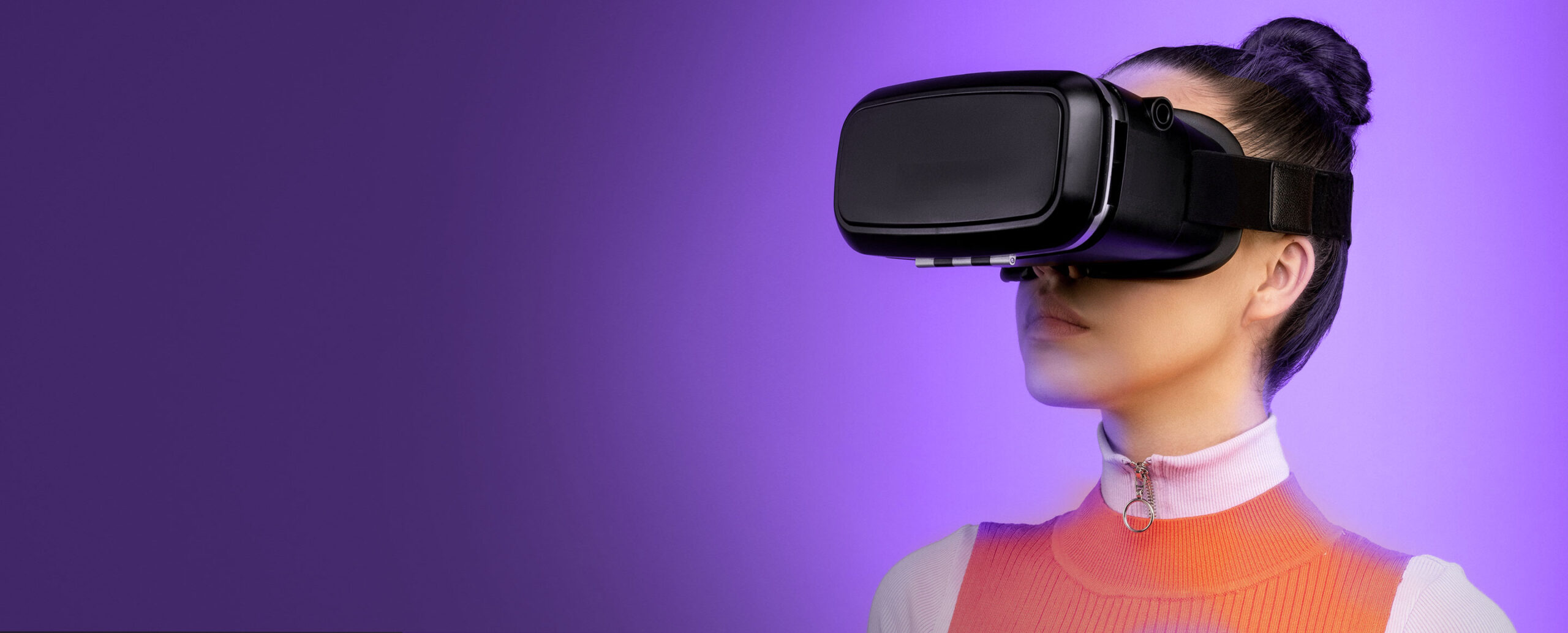Image of a woman wearing virtual reality goggles and orange dress with a purple background